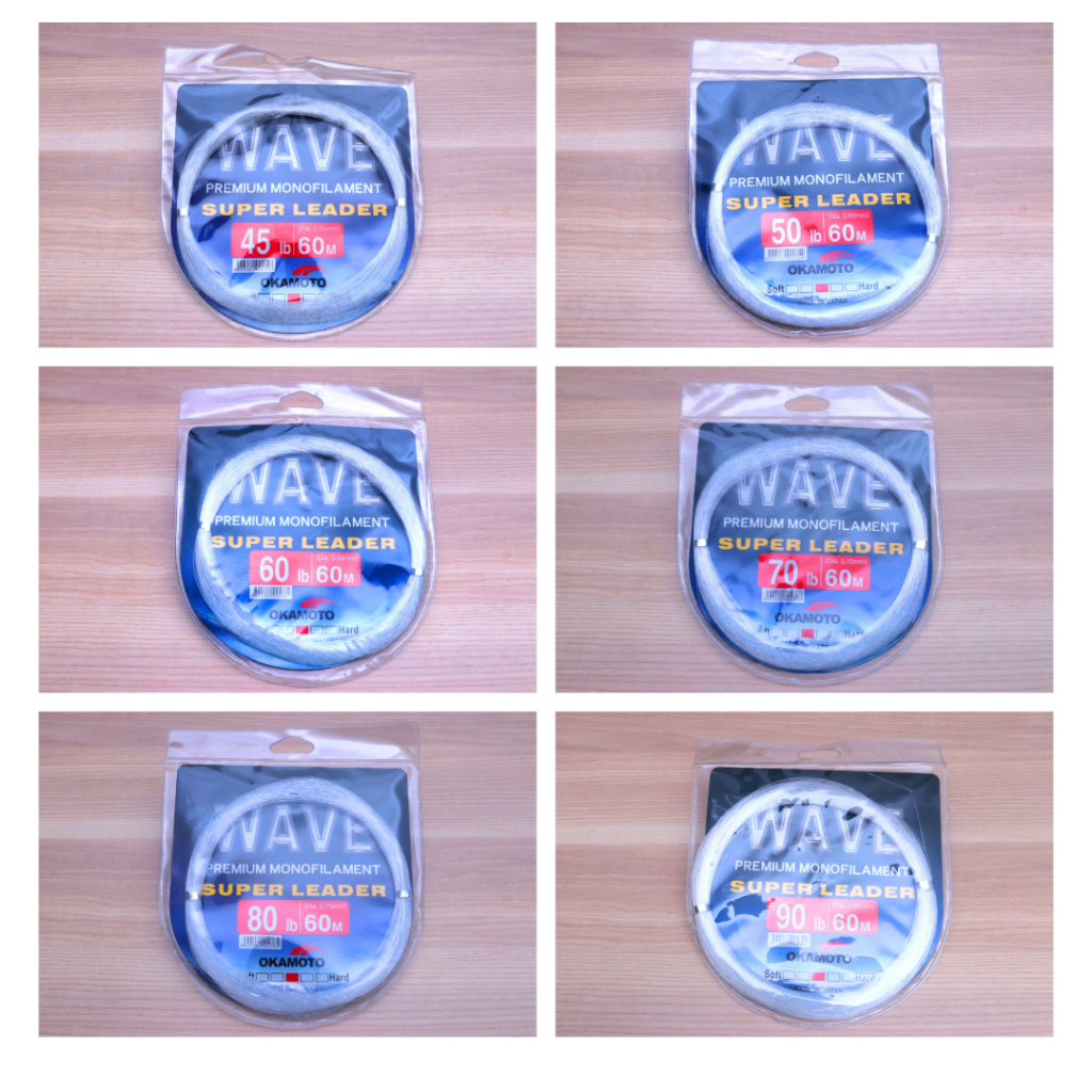 Six Okamoto Wave Super Soft Leader premium monofilament leader line (50-80lb) in blue packages on wooden table.