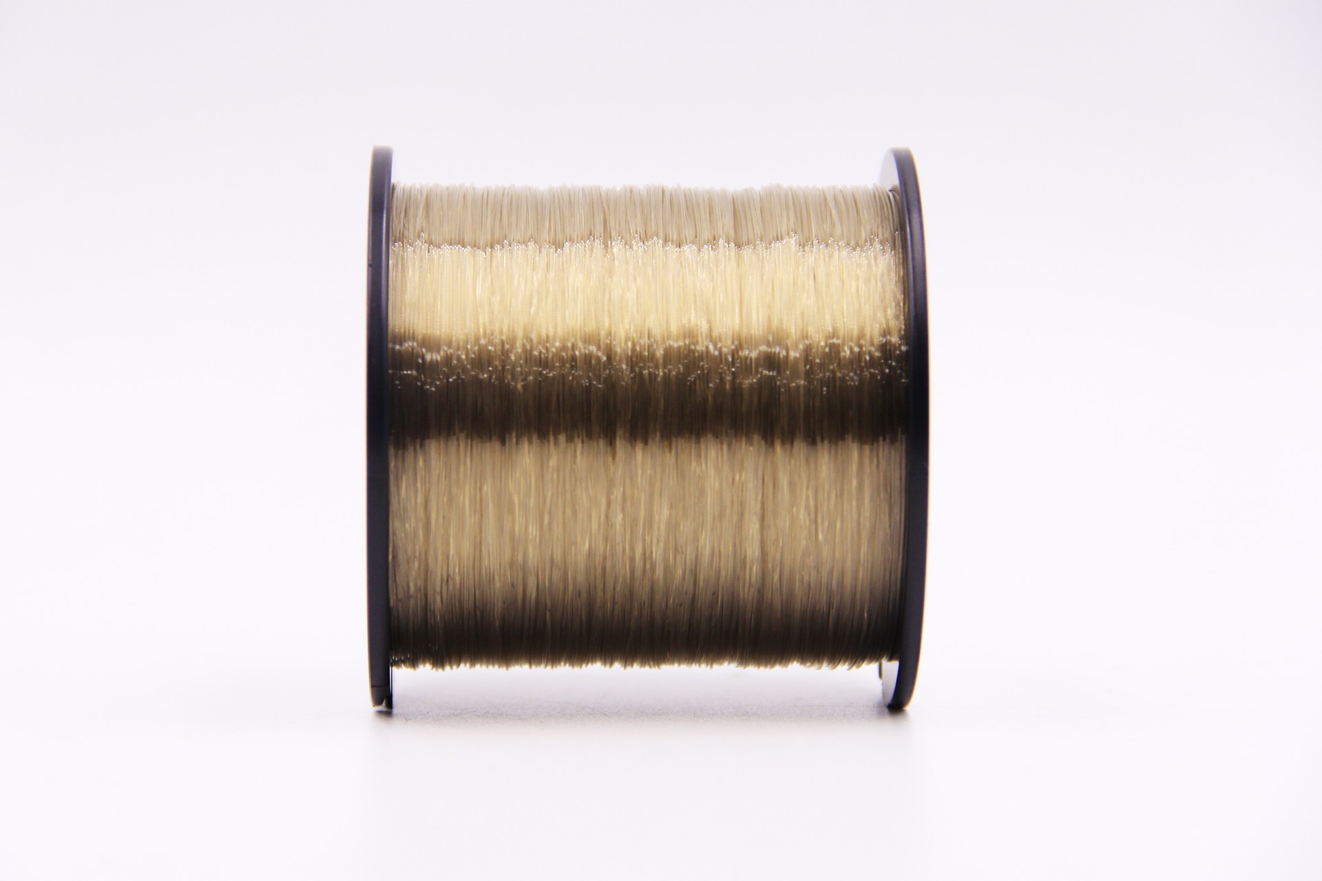 VFOX Invisible Key Fishing Line spool in light old gold, tightly wound on black flanges with smooth fluorocarbon shine