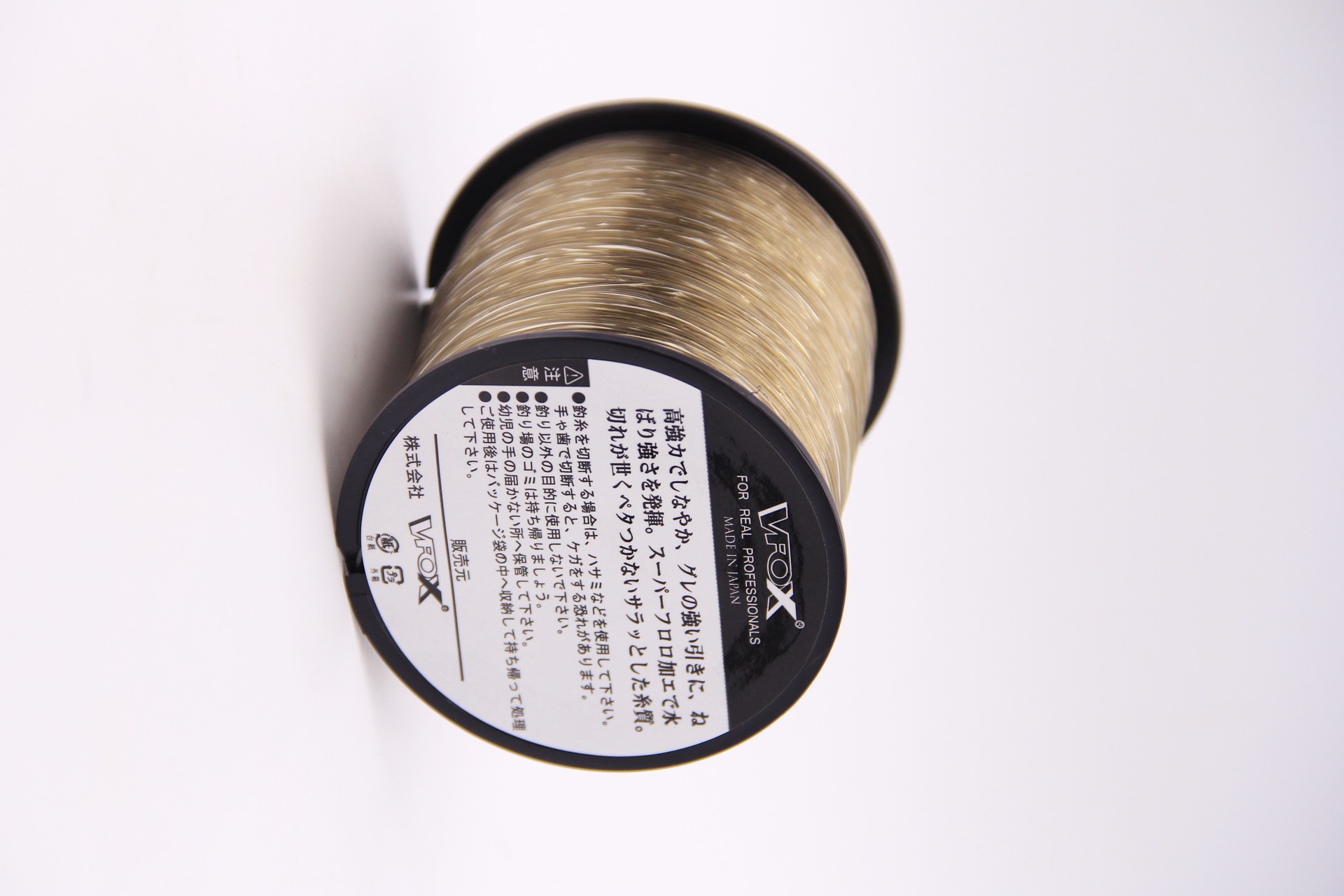 VFOX Invisible Key Fishing Line spool in light old gold, side view of label and wound line on white background