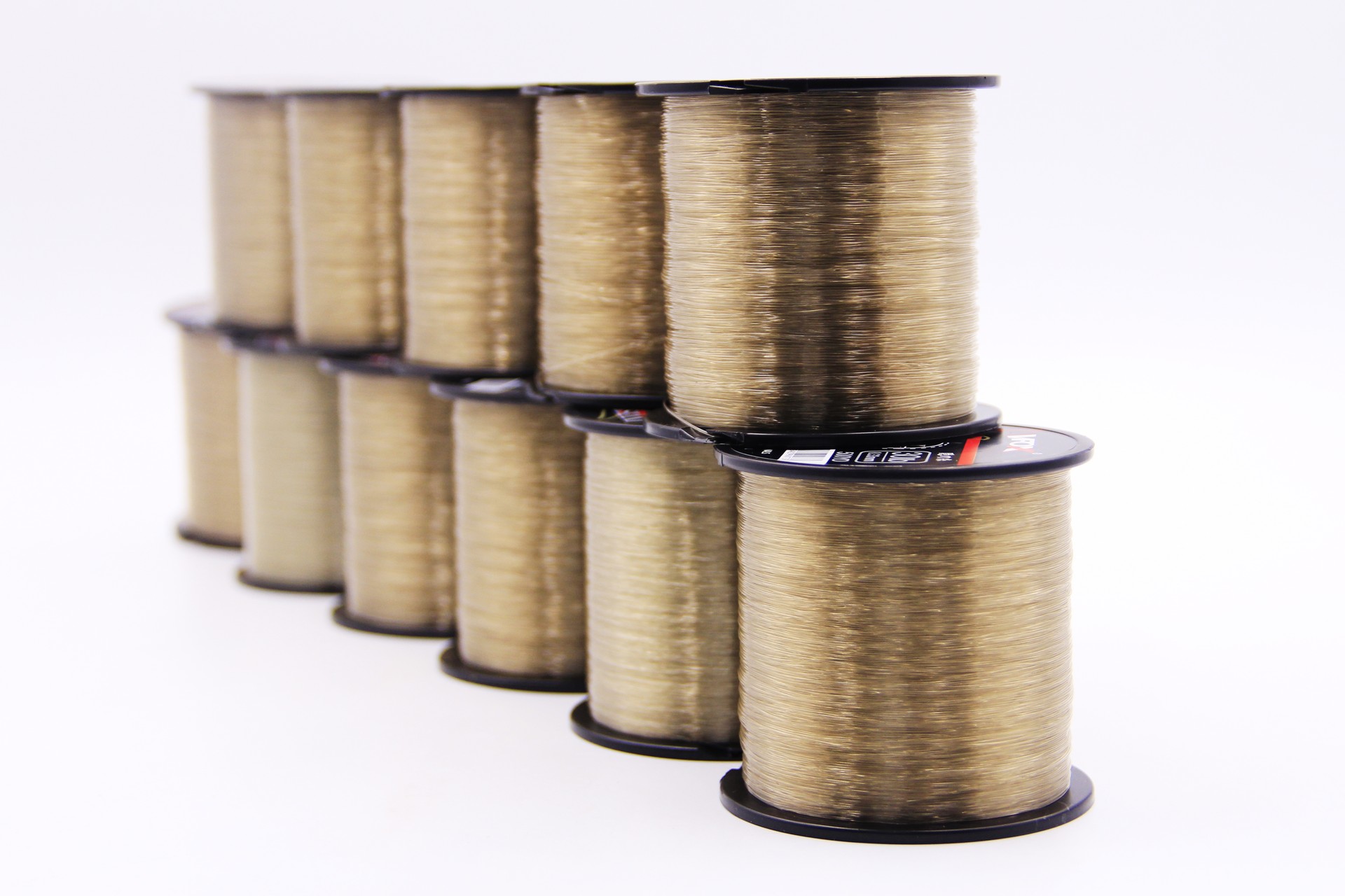 Stack of VFOX Invisible Key Fishing Line spools in Light Old Gold, showcasing smooth fluorocarbon-coated line on black cores